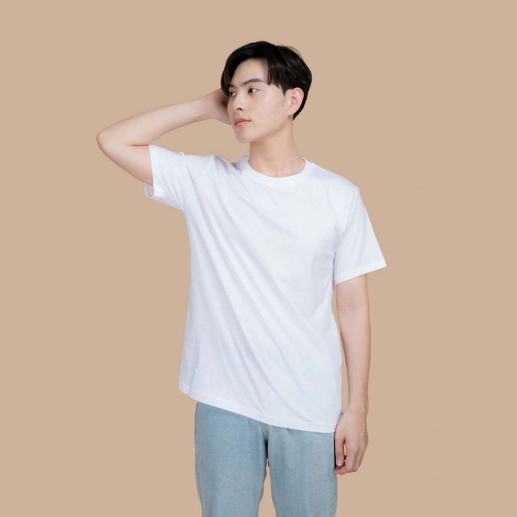 Young man in a white t-shirt and jeans posing against a neutral background